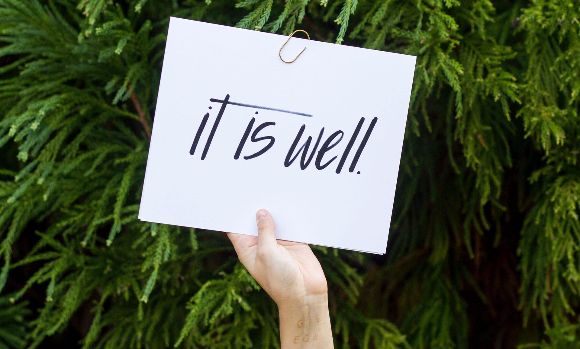 hand holding "it is well" sign